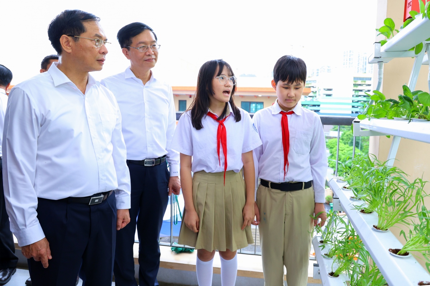 Phó Thủ tướng Bùi Thanh Sơn và đồng chí Trần Quang Dũng - Phó Bí thư thường trực Đảng ủy Petrovietnam nghe các em học sinh giới thiệu về “không gian xanh” tại Trường THCS Tây Mỗ 3.