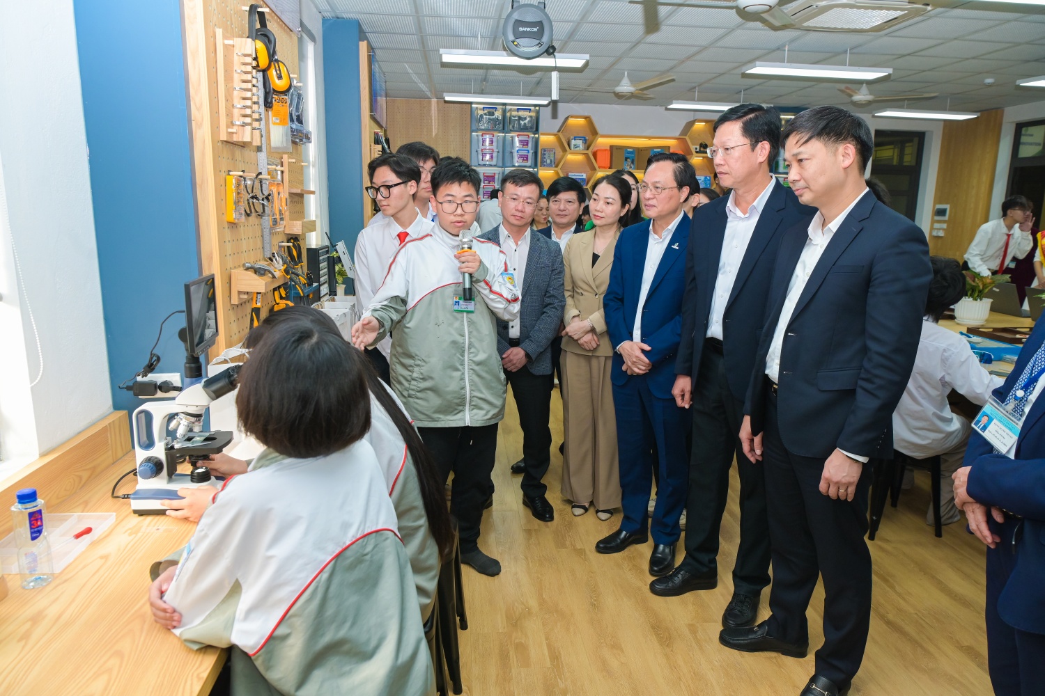 Các đại biểu nghe học sinh giới thiệu về trang thiết bị tại phòng thực hành giáo dục STEM.